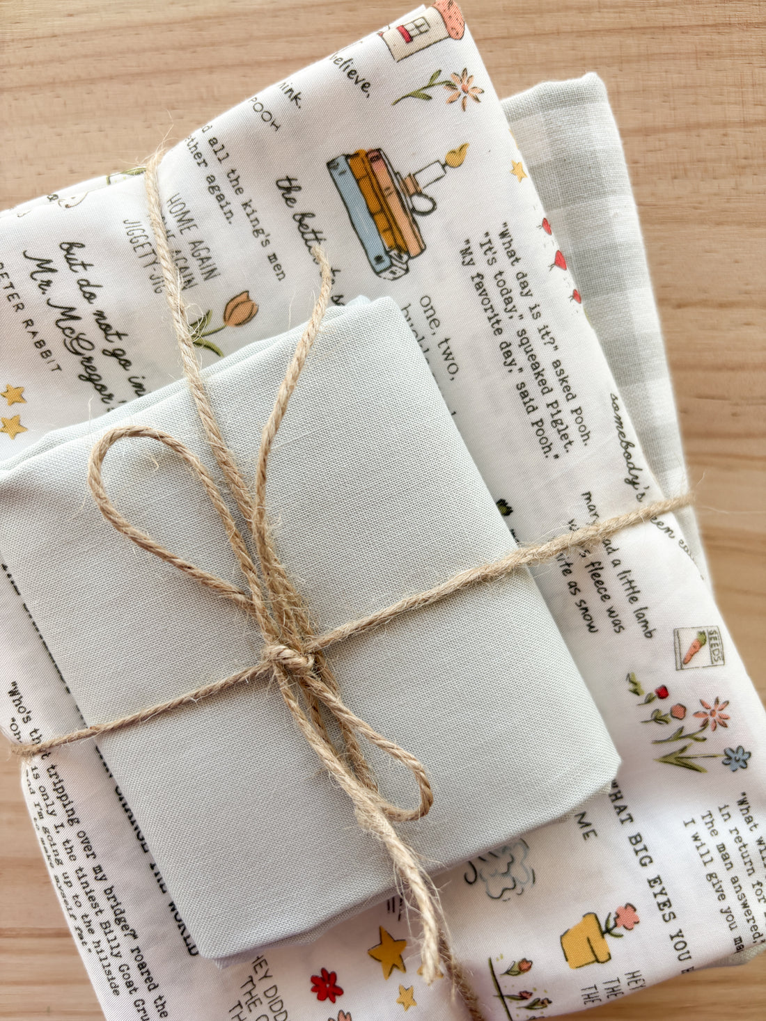 Fabric bundle with nursery rhyme text and small pictures with white and pale greens tied with twine