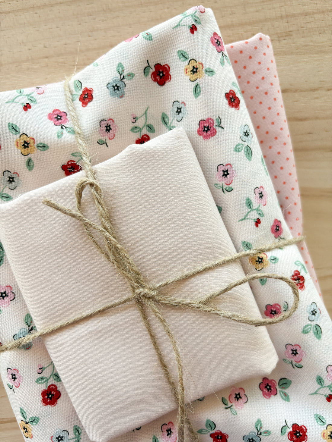 Bundle of fabric with small colourful flowers with white and pink tied with twine