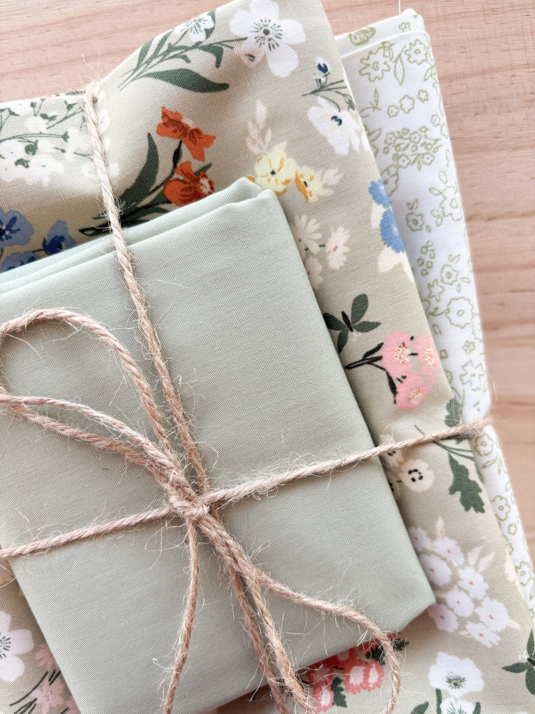 Bundle of fabric with colourful flowers with cream and white tied with twine
