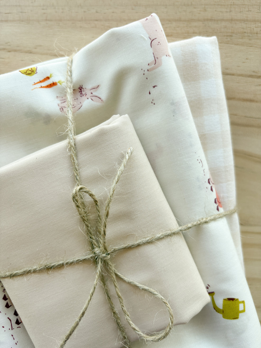 Fabric bundle with bunnies, geese, vegetables, watering cans, with light pink and cream tied with twine