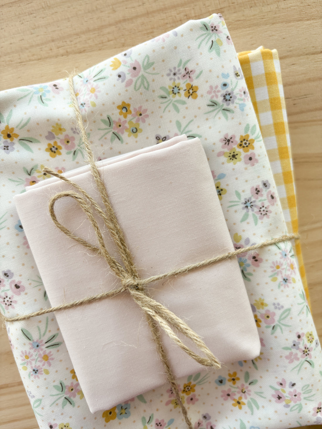 Fabric bundles with colourful flowers with pink, cream and golden yellows wrapped in twine