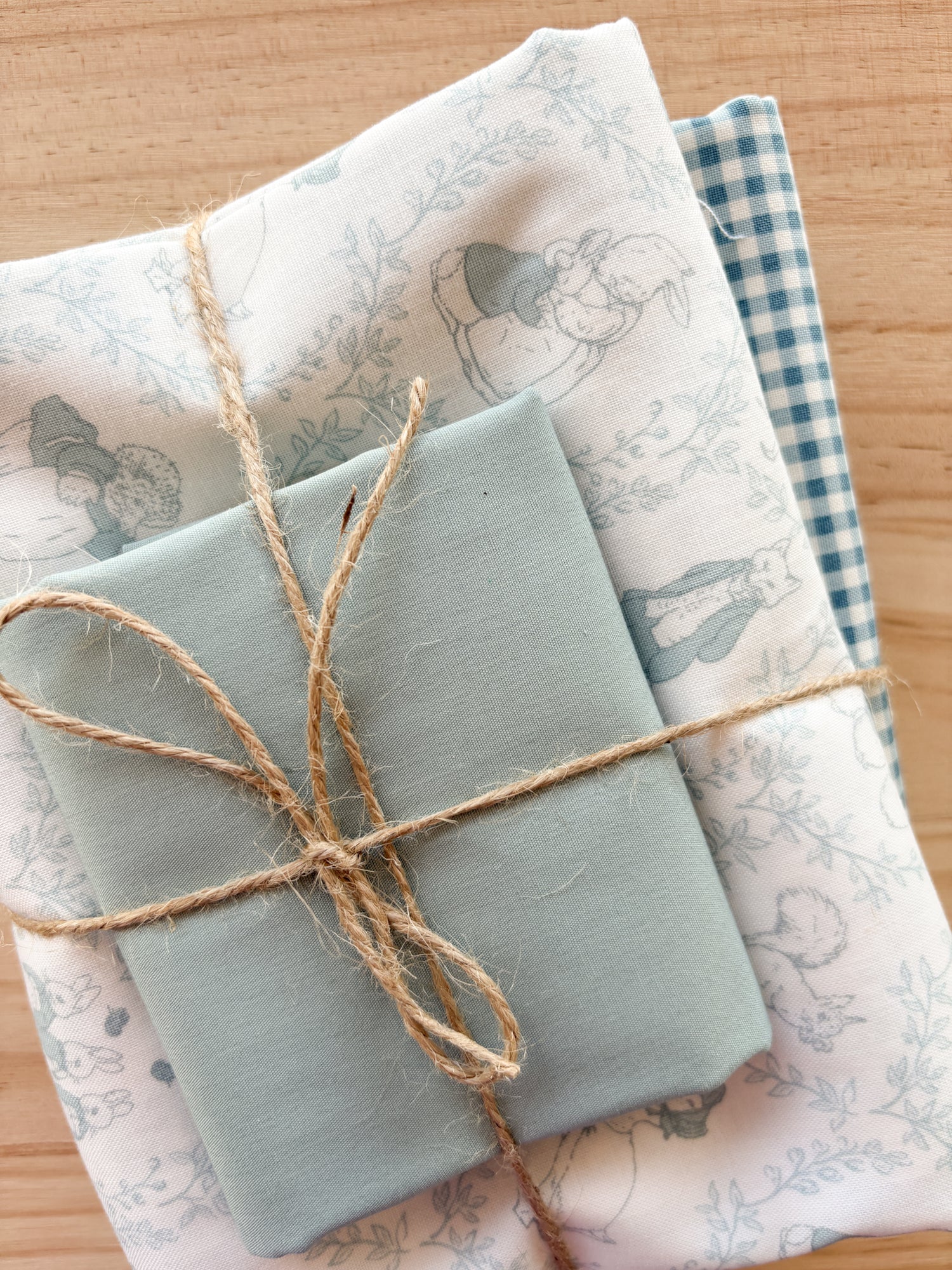 Bundle of fabric with light blues and bunny Beatrix Potter print tied with twine.