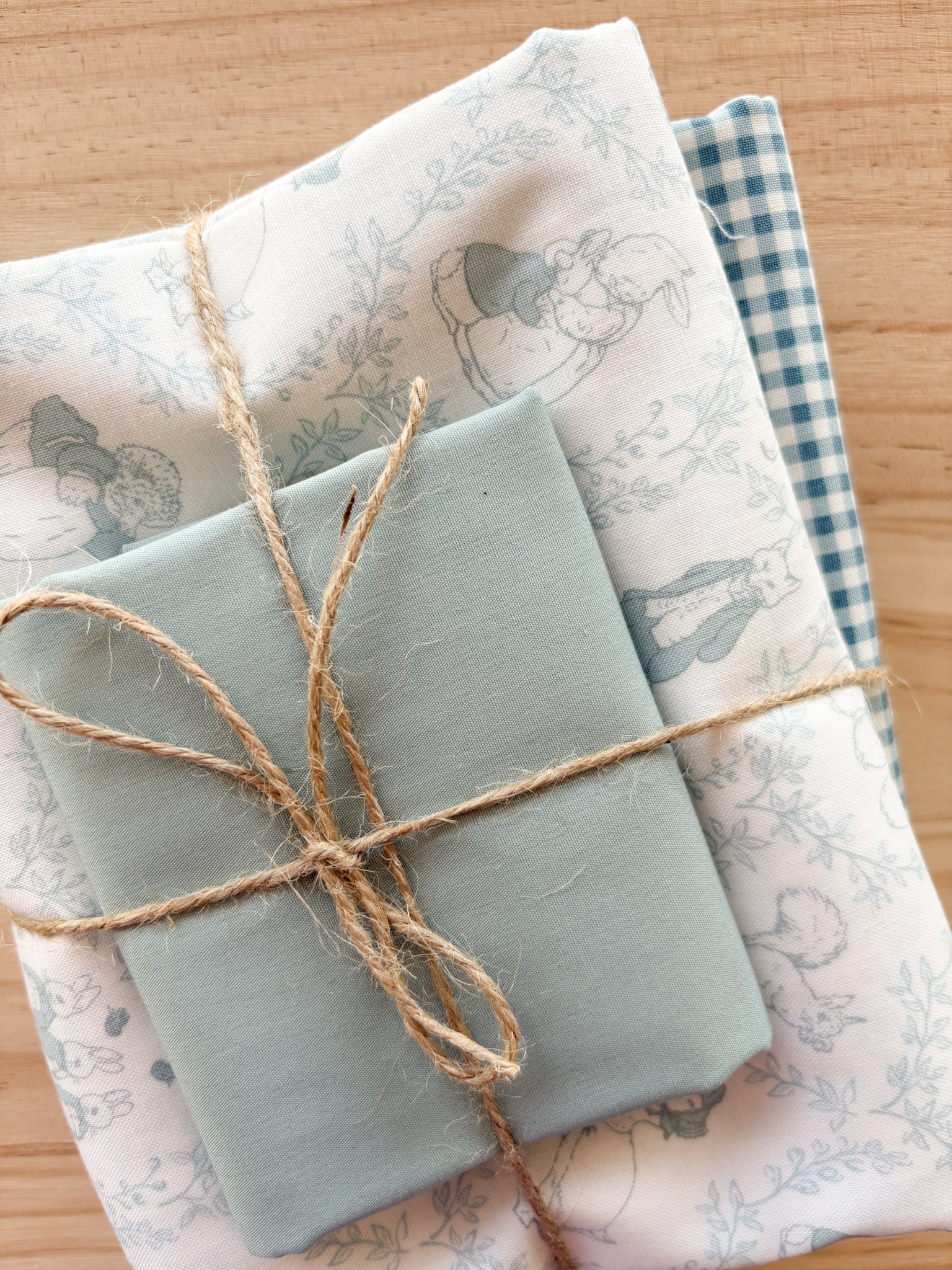 Bundle of fabric with light blues and bunny Beatrix Potter print tied with twine.